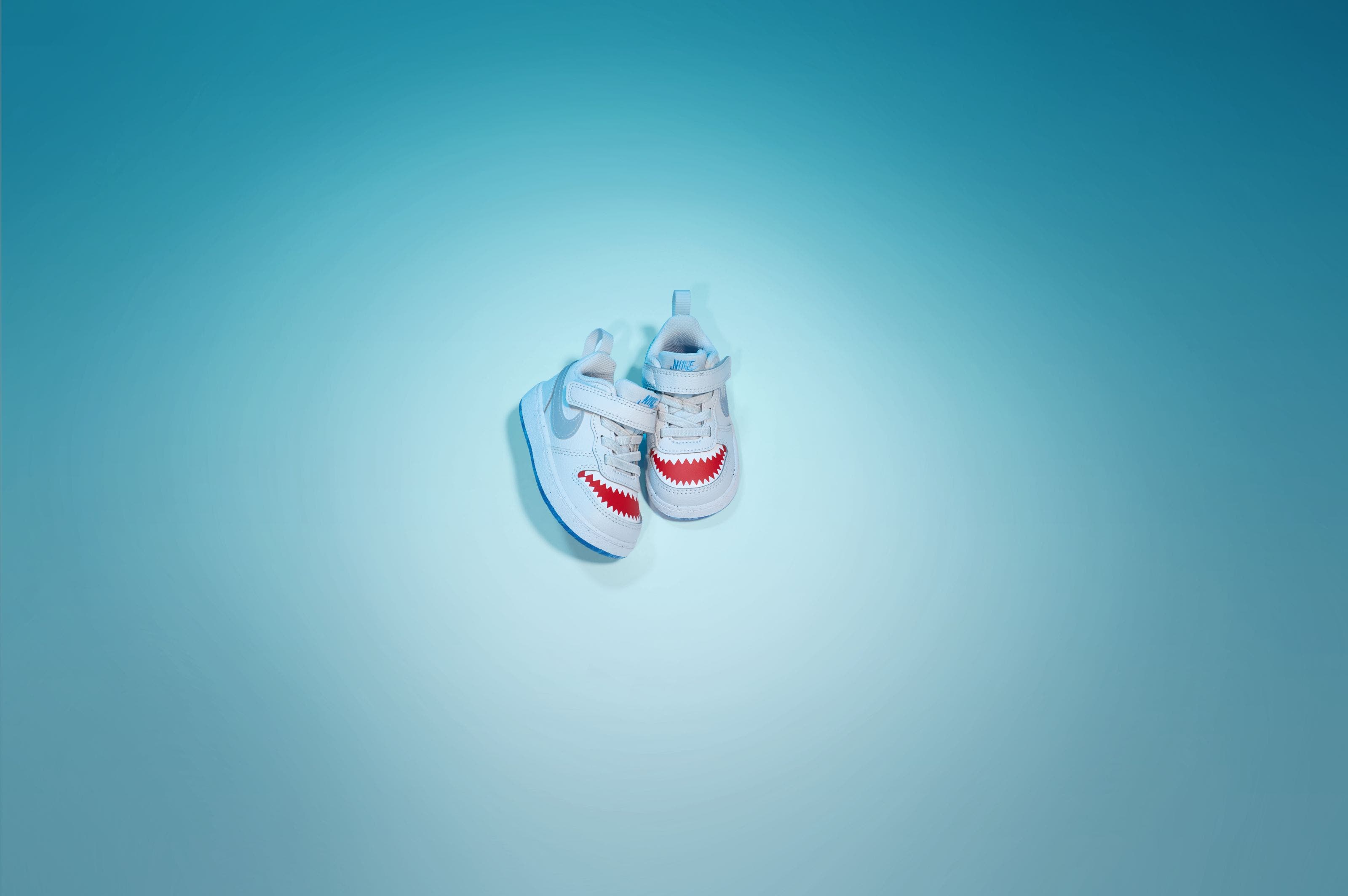 Nike infant sneakers in light blue with shark teeth graphic detail.