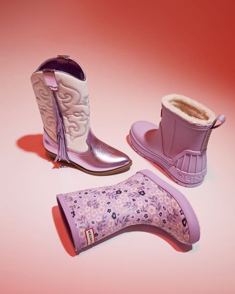 Lavender western and rain boots, one floral and one fleece-lined, on pink.