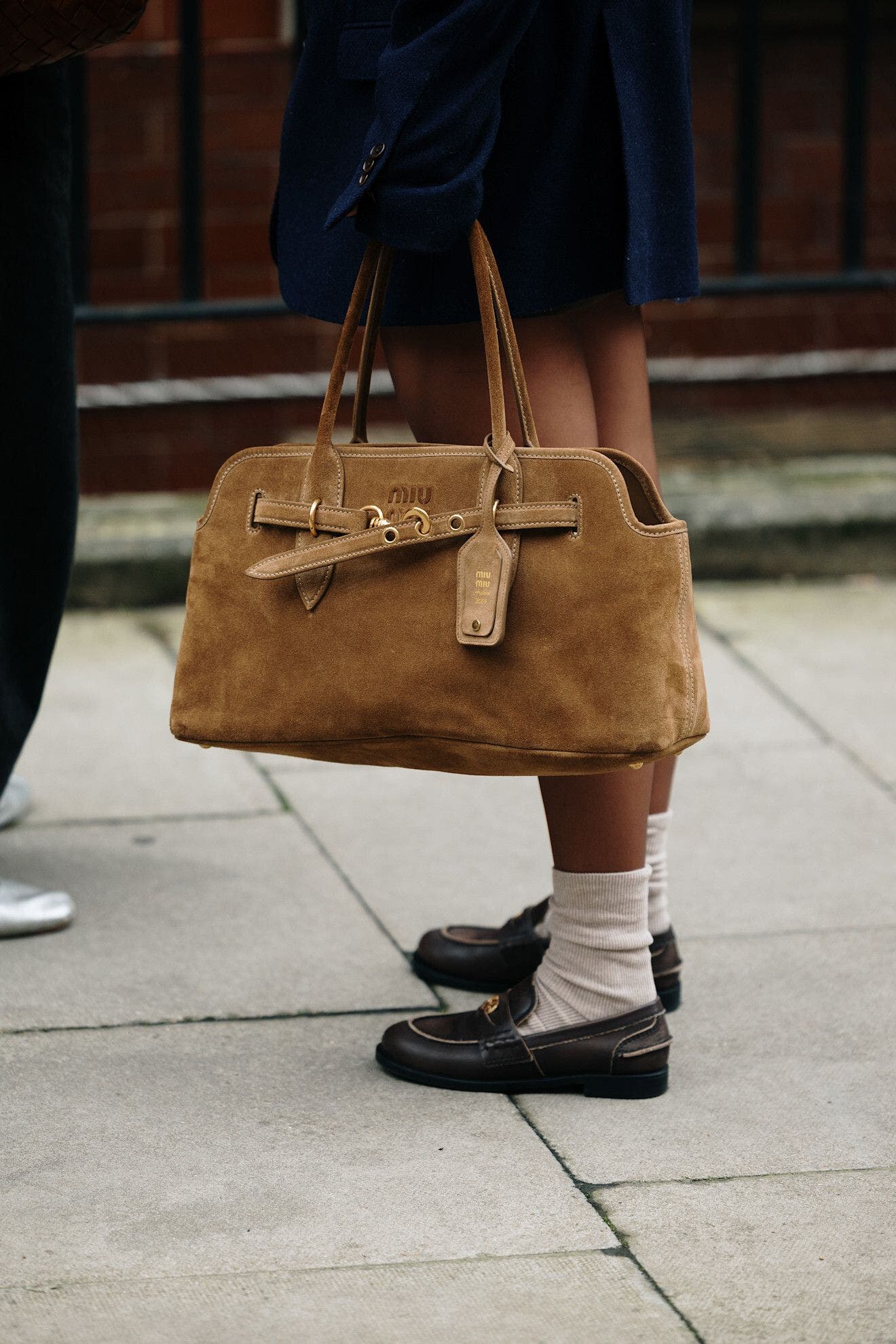 Person carrying a suede tote bag at London Fashion Week.