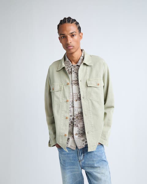 A mean wearing shirt jacket, shirt, and denim pants.