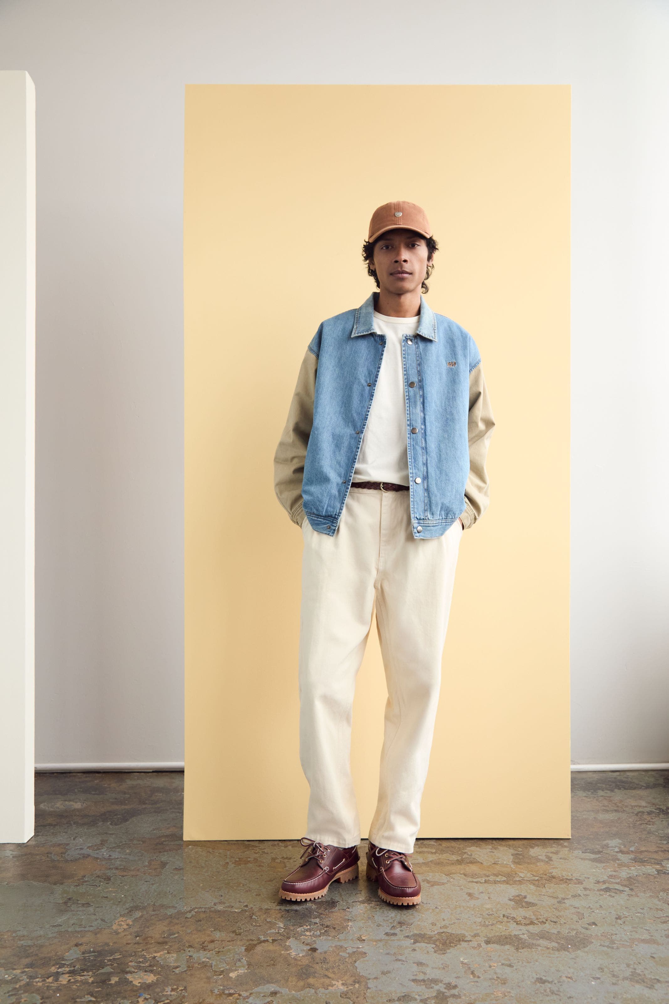 A man wearing a denim-front varsity jacket.