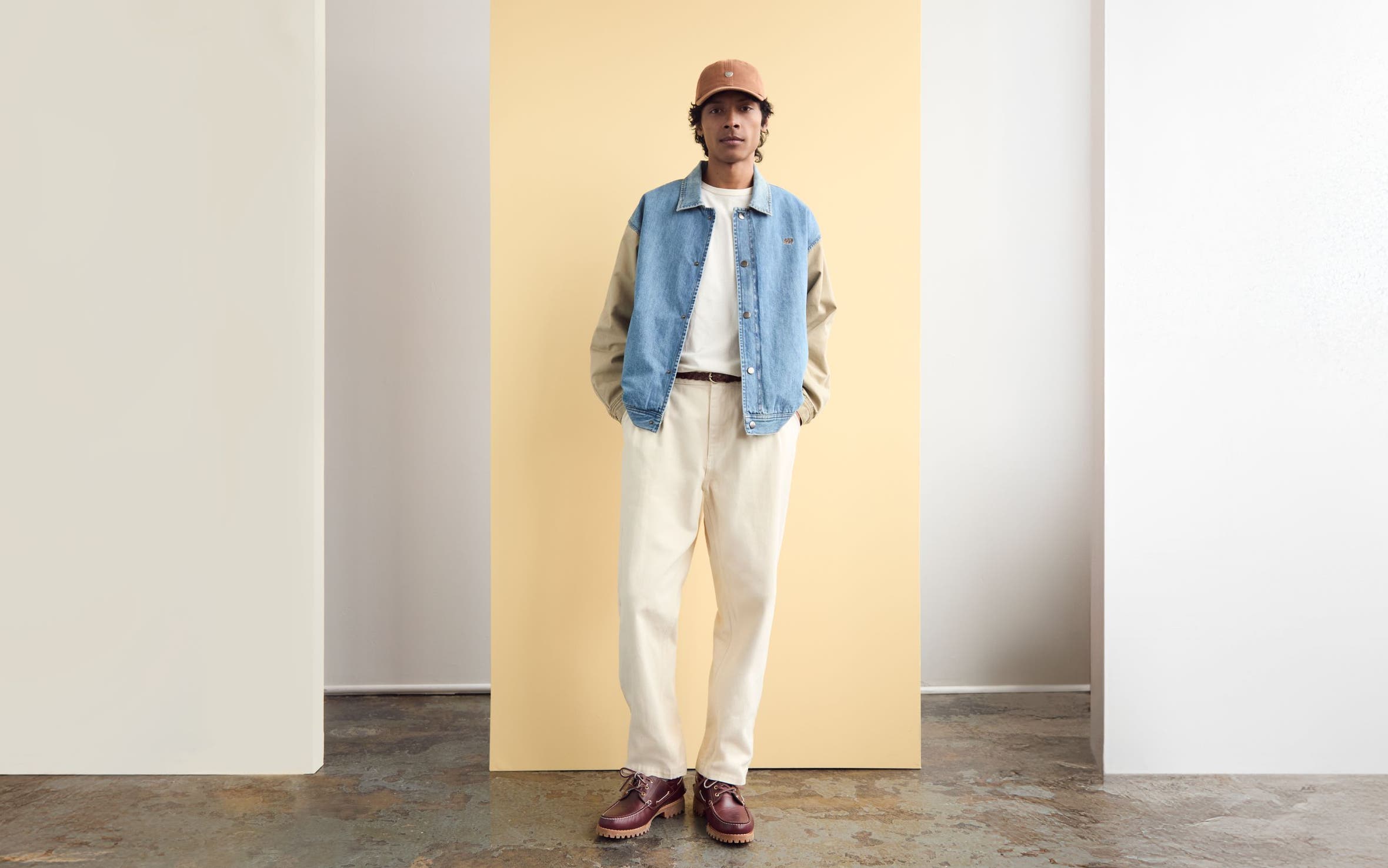 A man wearing a two-tone denim jack with white jeans and a T-shirt.