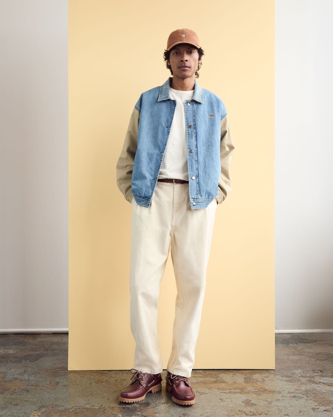 A man wearing a two-tone denim jack with white jeans and a T-shirt.