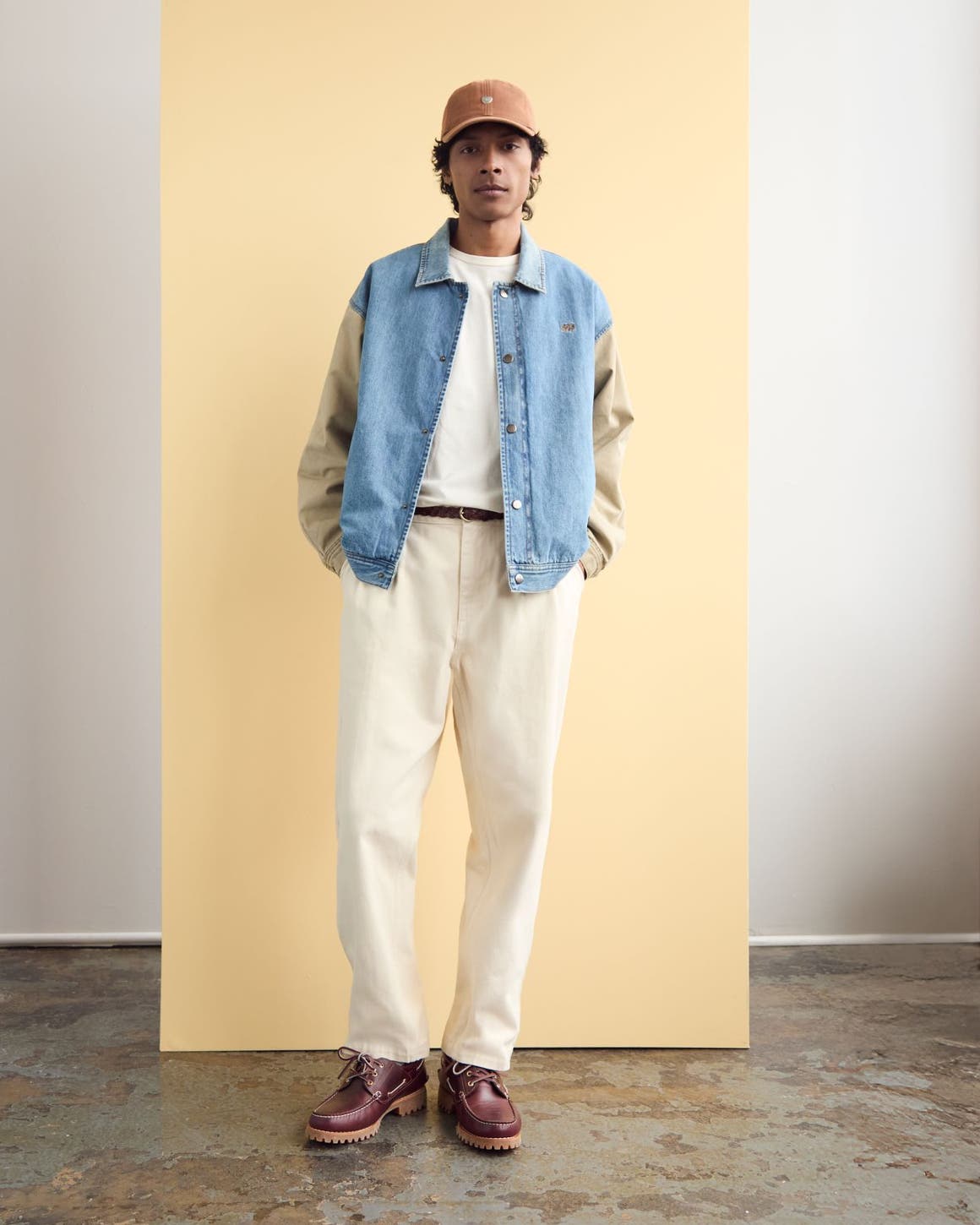Man wearing a cap, jacket, T-shirt, white denim and boots.