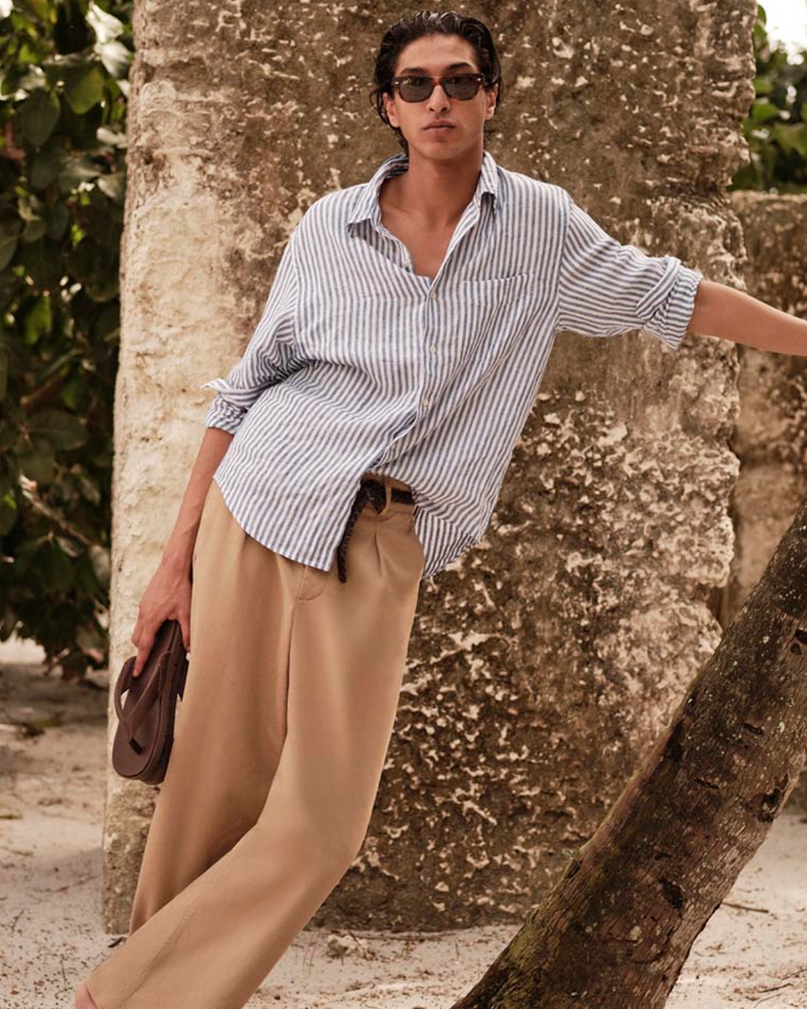 A man wearing a striped button down and linen pants.