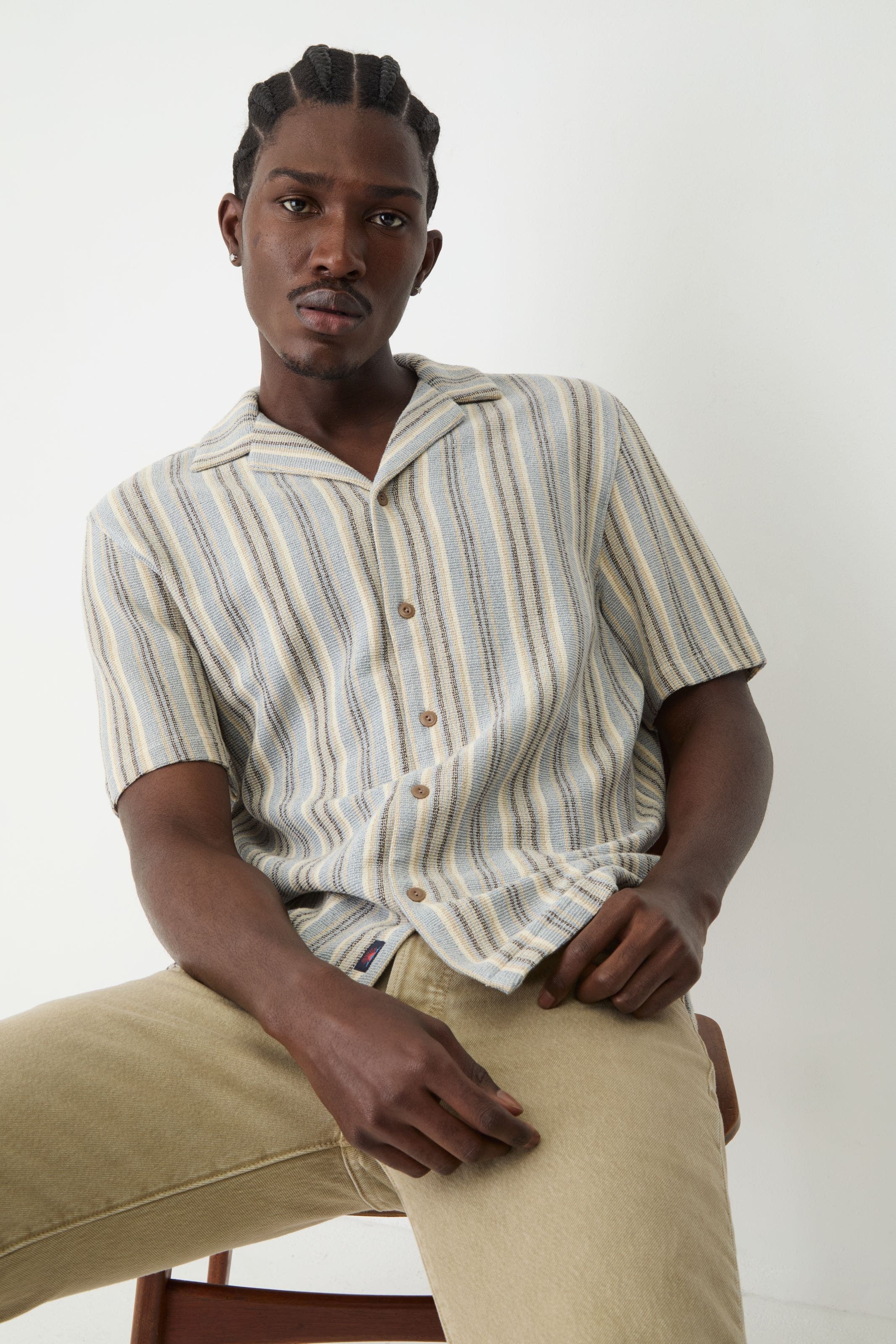 A man wearing striped short sleeve button up. 