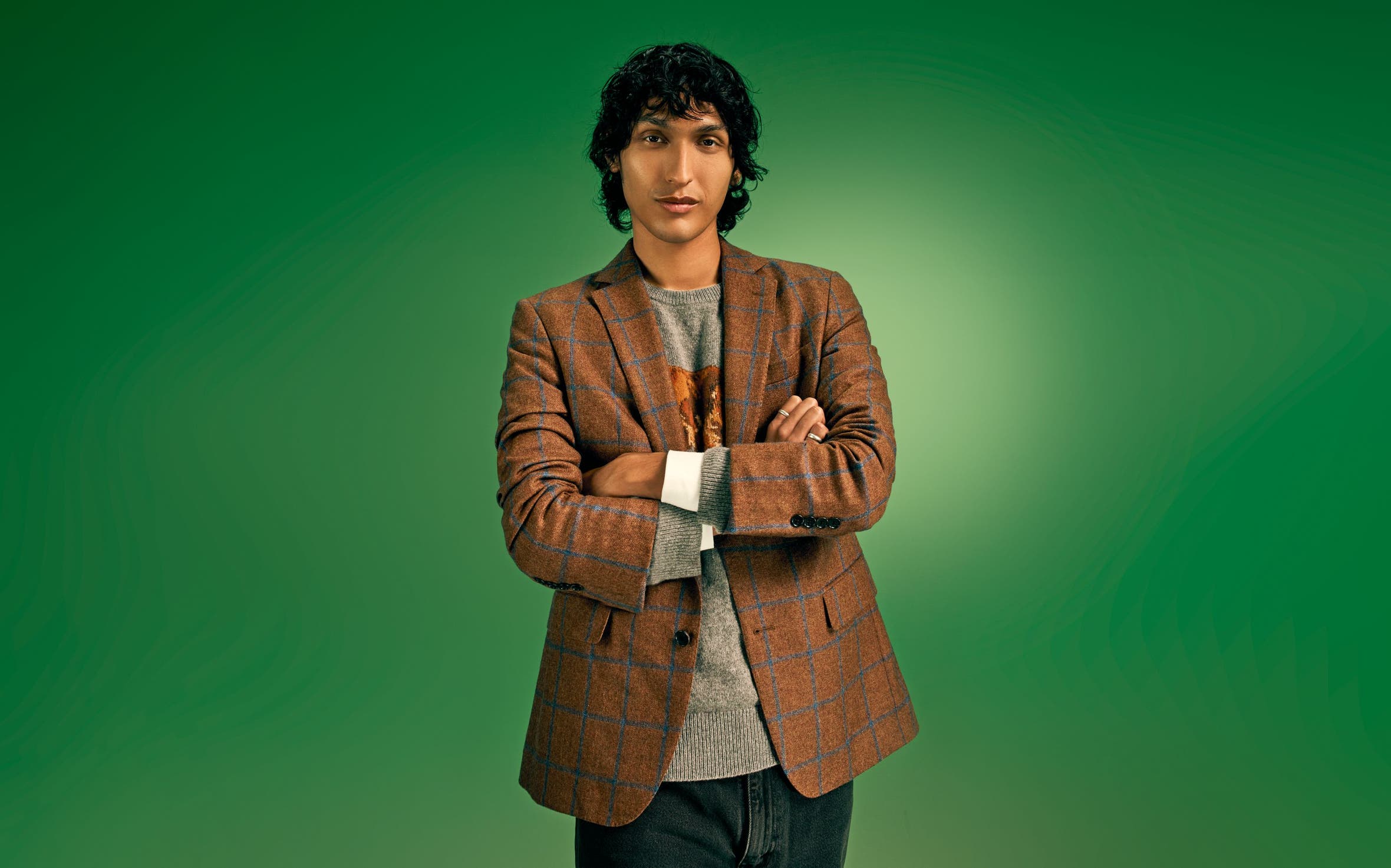 A man wearing a blazer over a sweater.