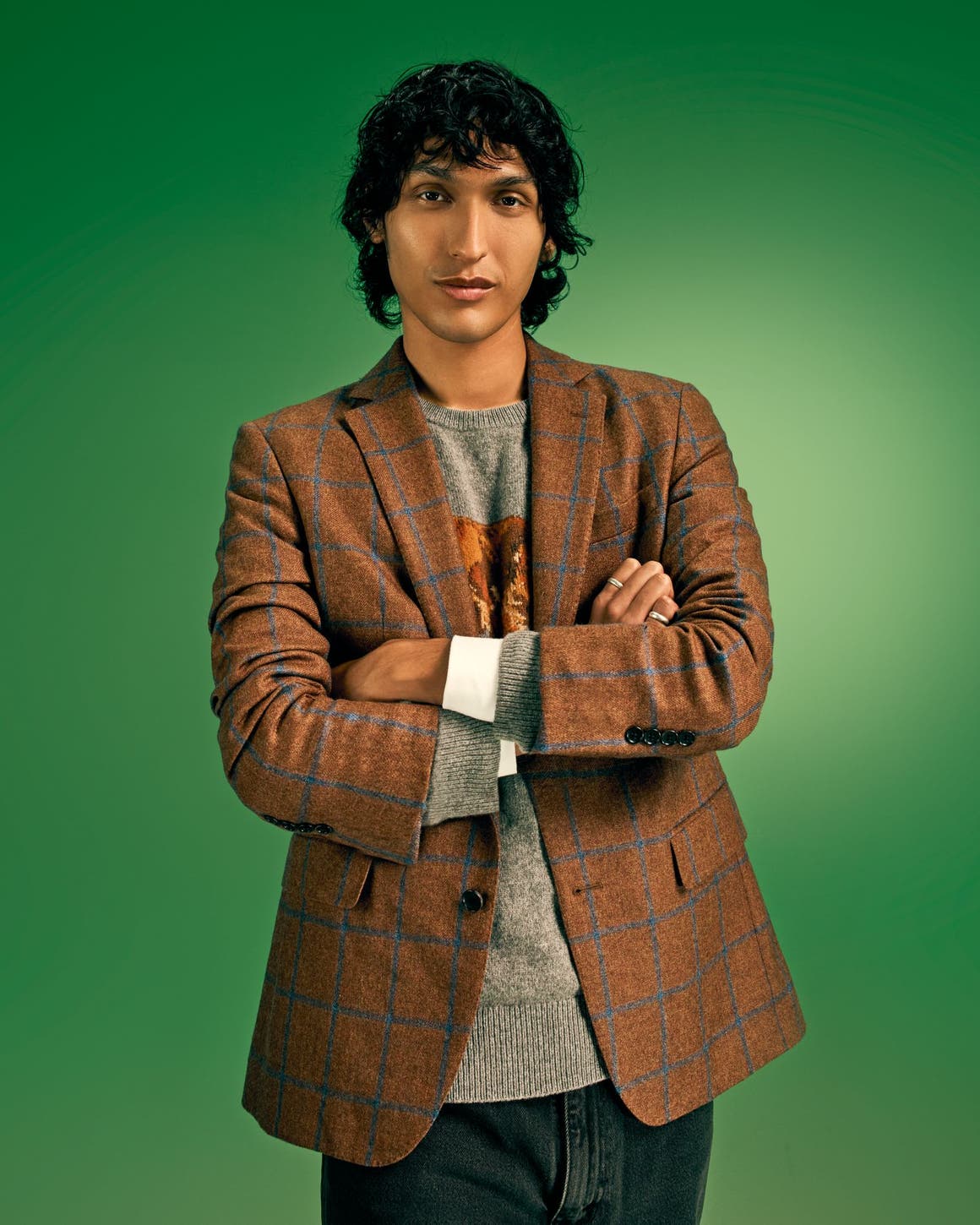 A man wearing a blazer over a sweater.