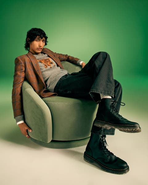 A man in a blazer, graphic tee and jeans.