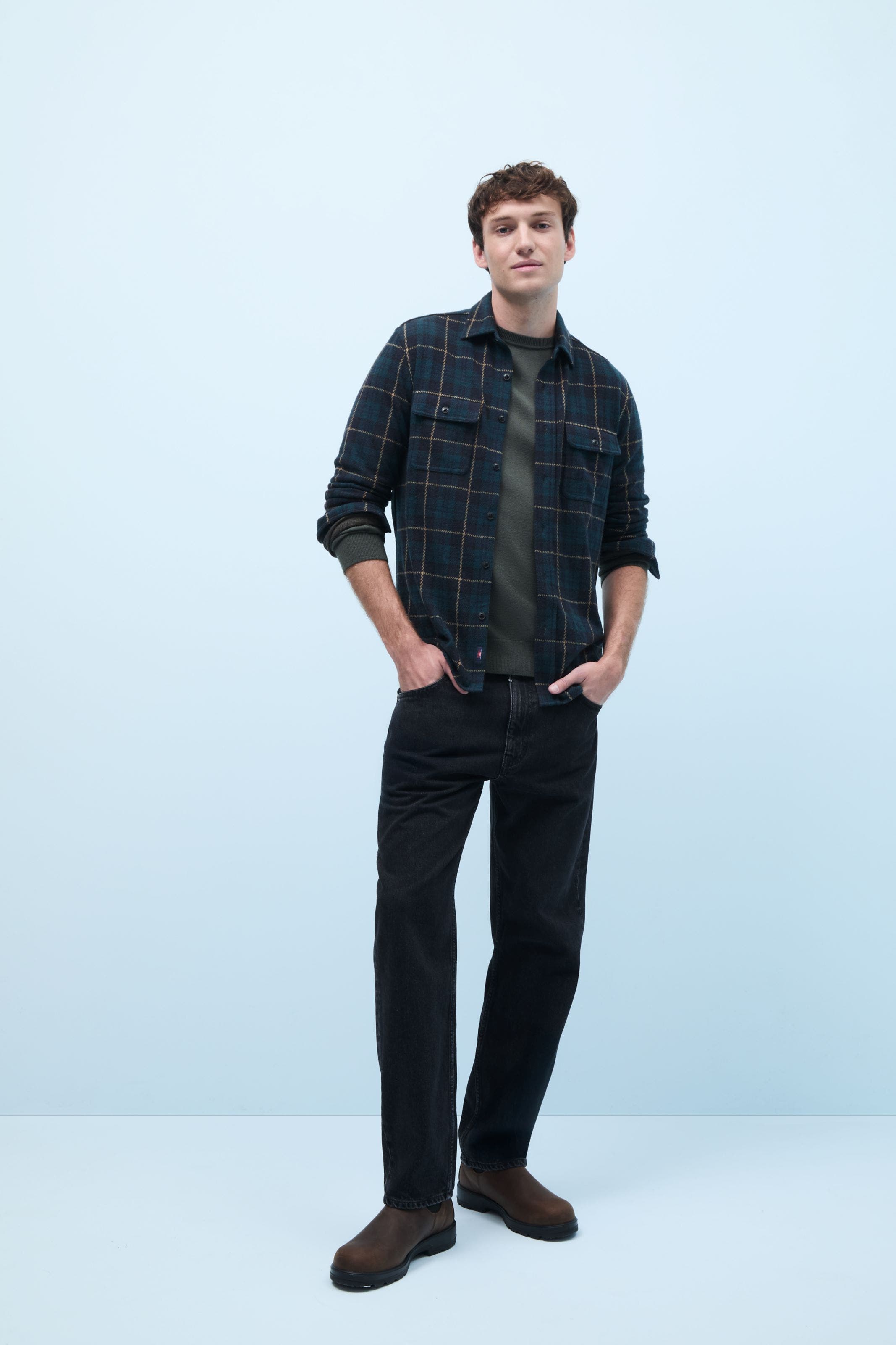 A man wearing a plaid flannel shirt over a T-shirt.