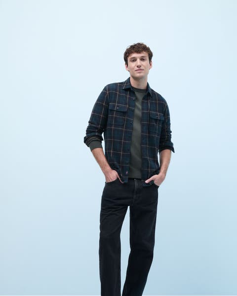 A man wearing a plaid flannel shirt over a T-shirt.
