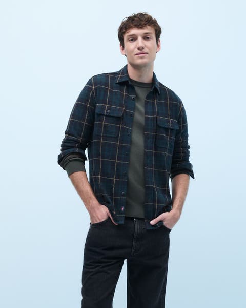 A man wearing a plaid flannel shirt over a T-shirt.