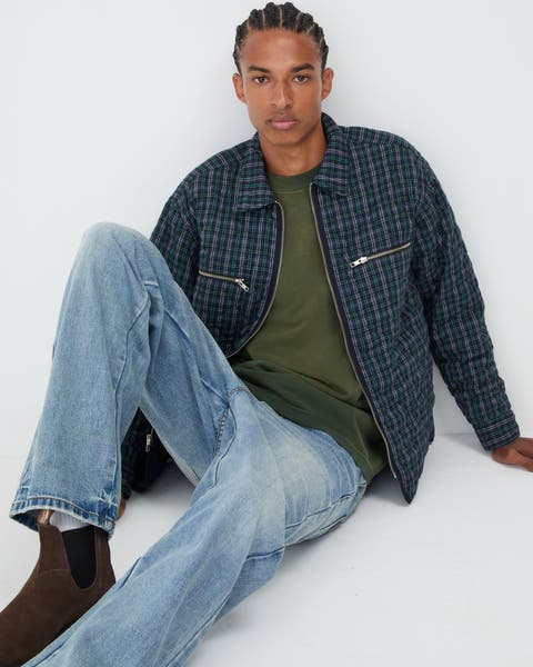 A Man sitting down wearing denim, t-shirt, and jacket.