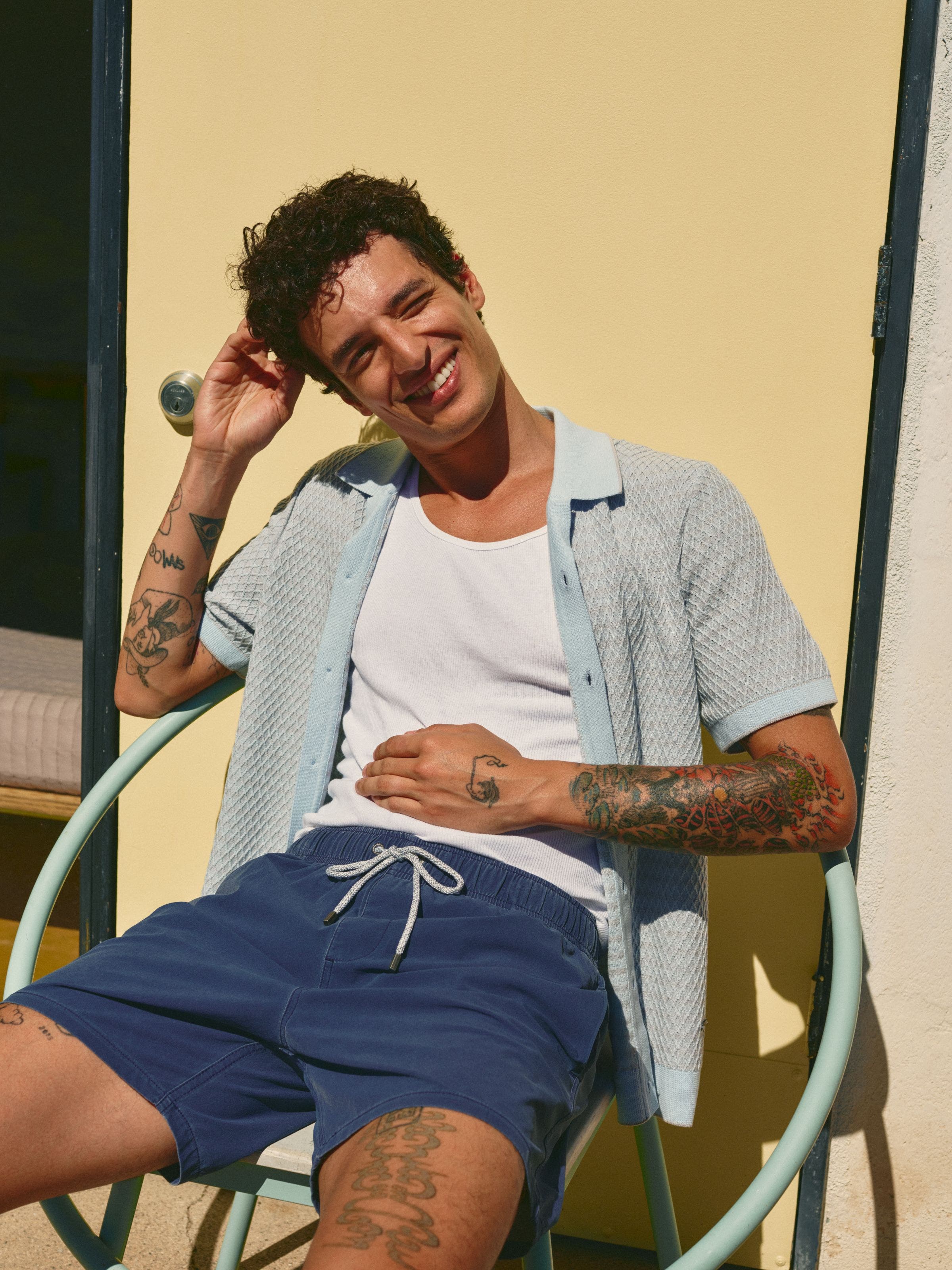 Man wearing short sleeve button-up and swim trunks.