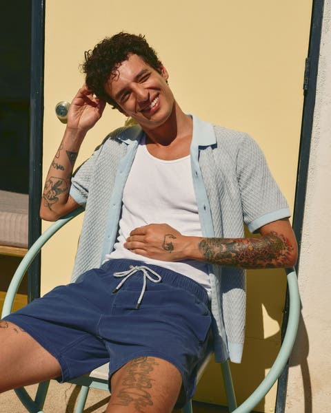 Man wearing a tank, short-sleeve cardigan and swim trunks.