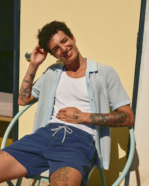 Man wearing a ribbed tank, short-sleeve cardigan and shorts.