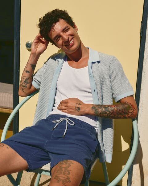 Man wearing short sleeve button-up and swim trunks.