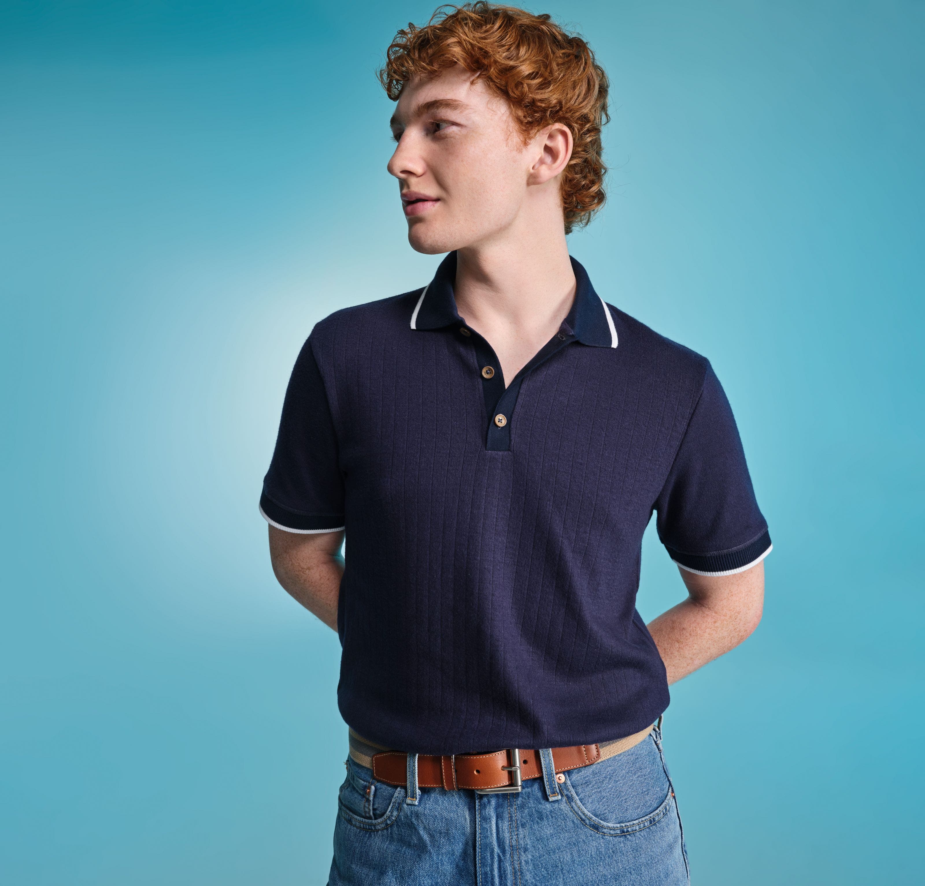 Man wearing navy blue polo with blue jeans.