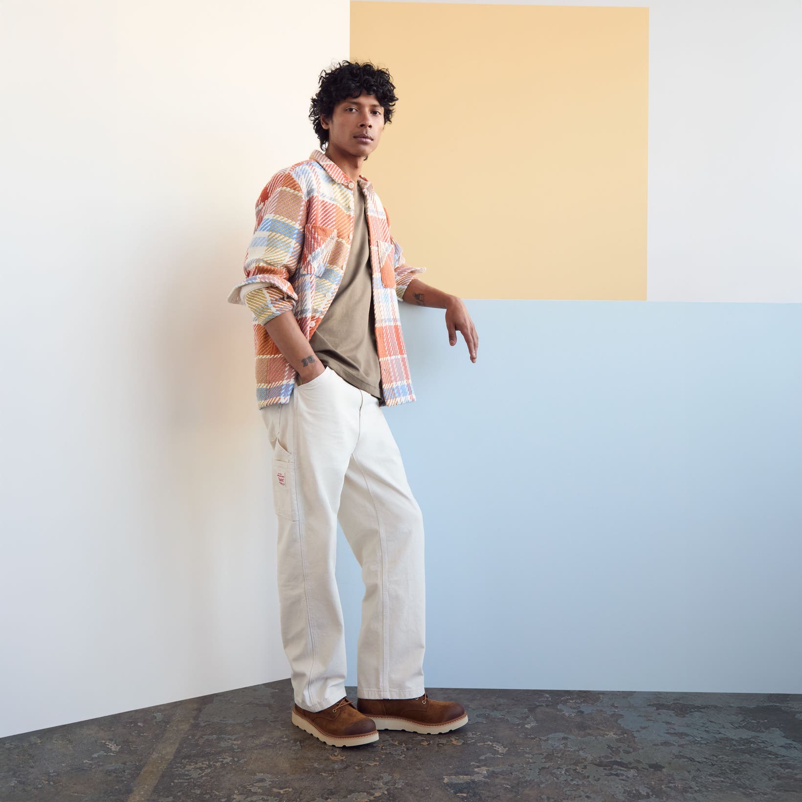 A man in a colorful shirt jacket with neutral tee and pants.