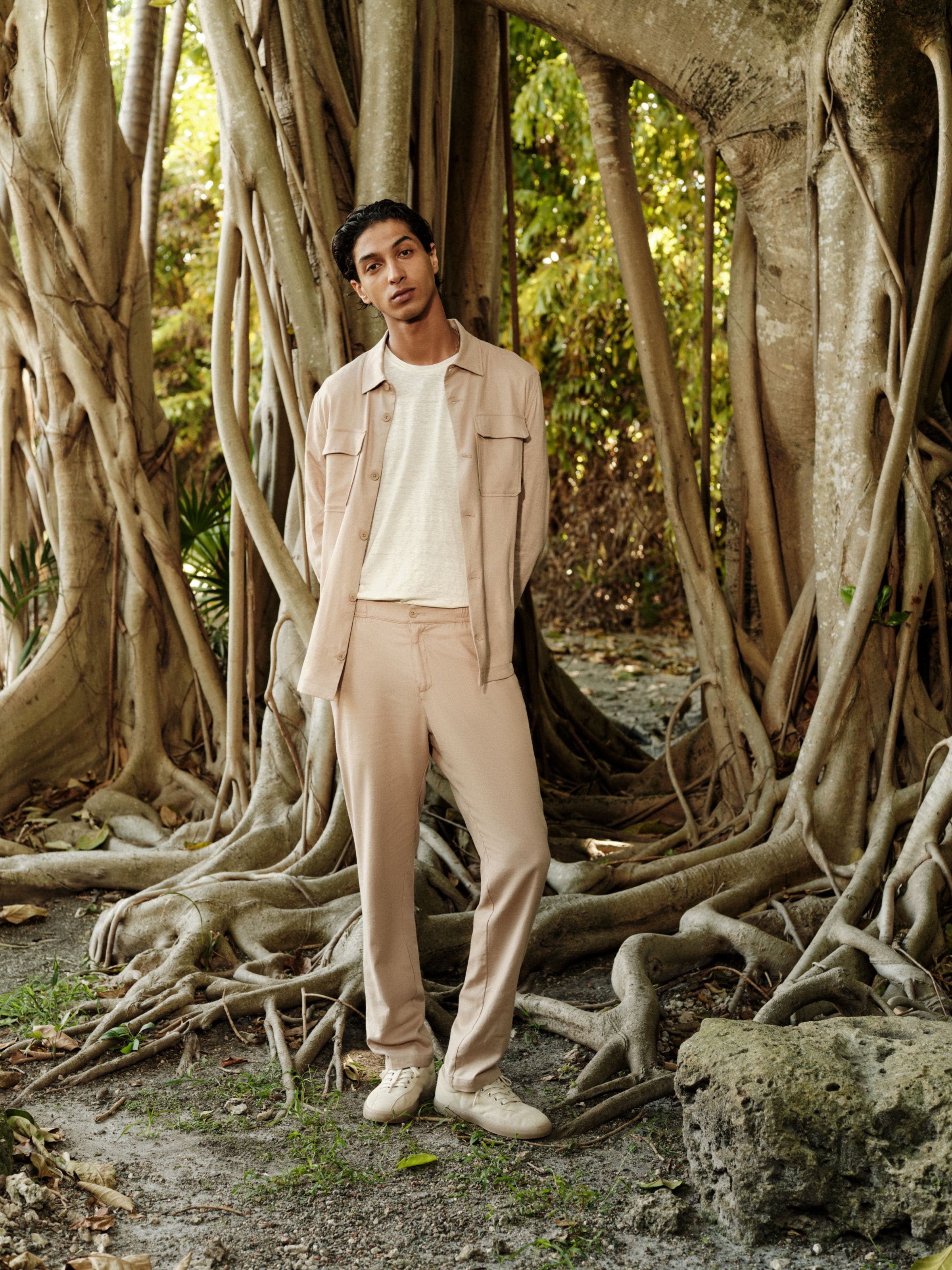 Man wearing a beige matching shirt and pants set with a white tee.