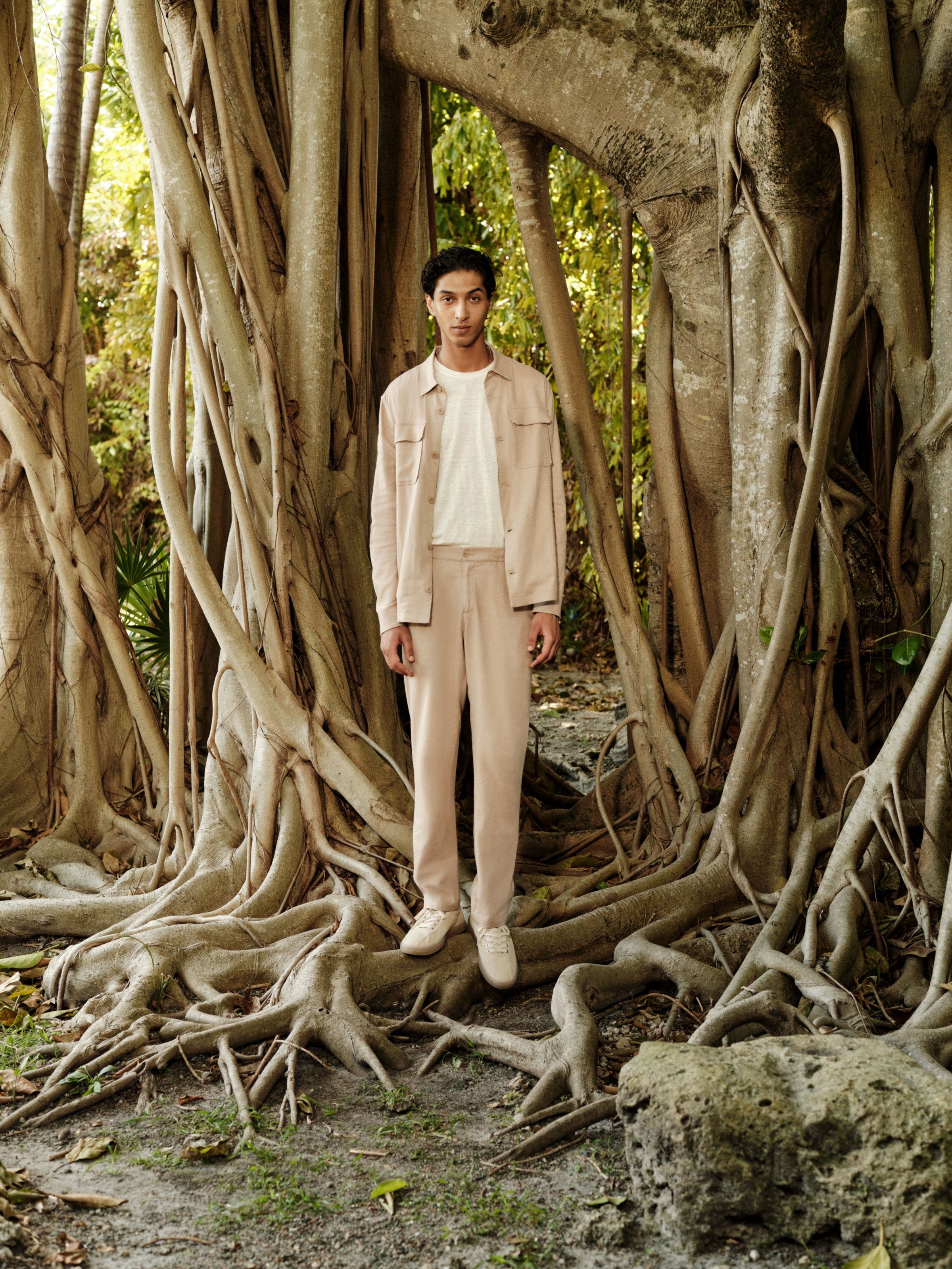 A man wearing a shirt jacket, T-shirt, relaxed trousers and sneakers.