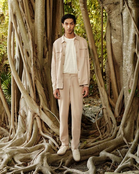 A man wearing a shirt jacket, T-shirt, relaxed trousers and sneakers.