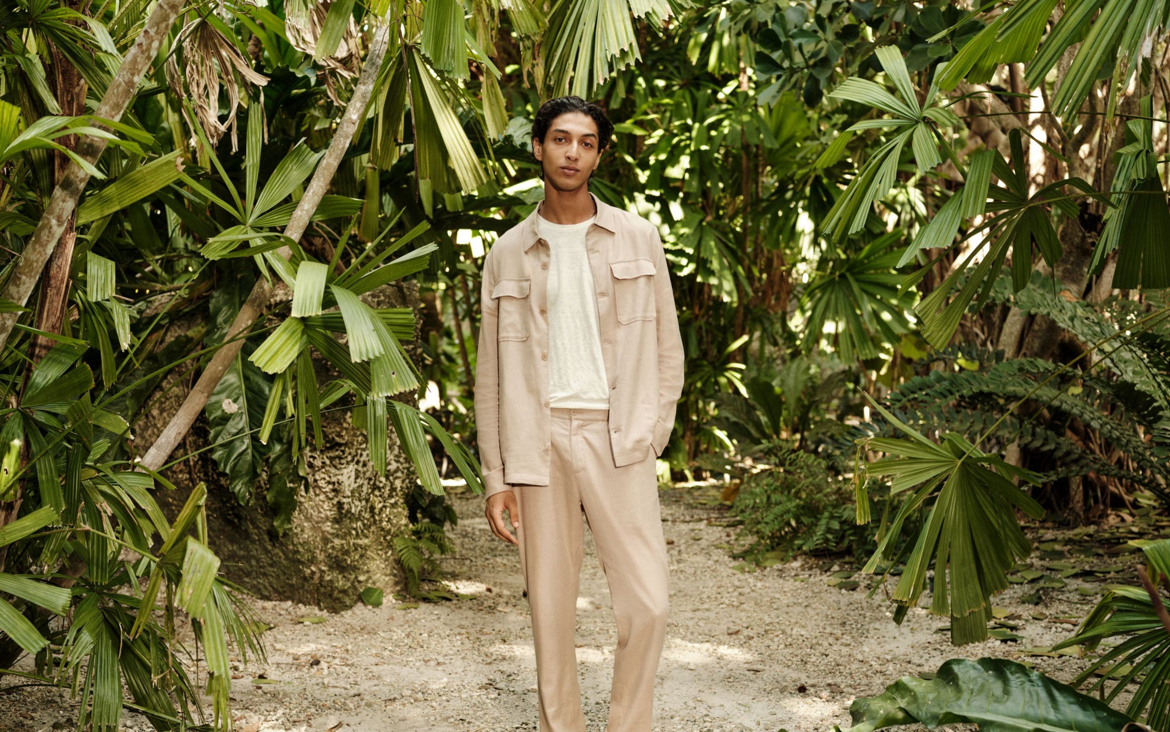 A man wearing a shirt jacket, T-shirt, relaxed trousers and sneakers.