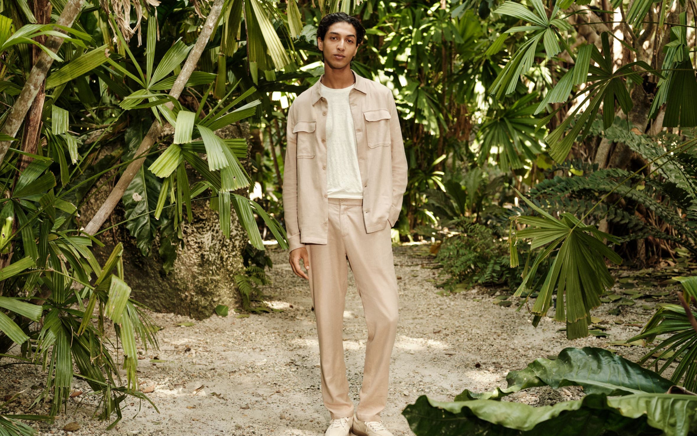 A man wearing a shirt jacket, T-shirt, relaxed trousers and sneakers.