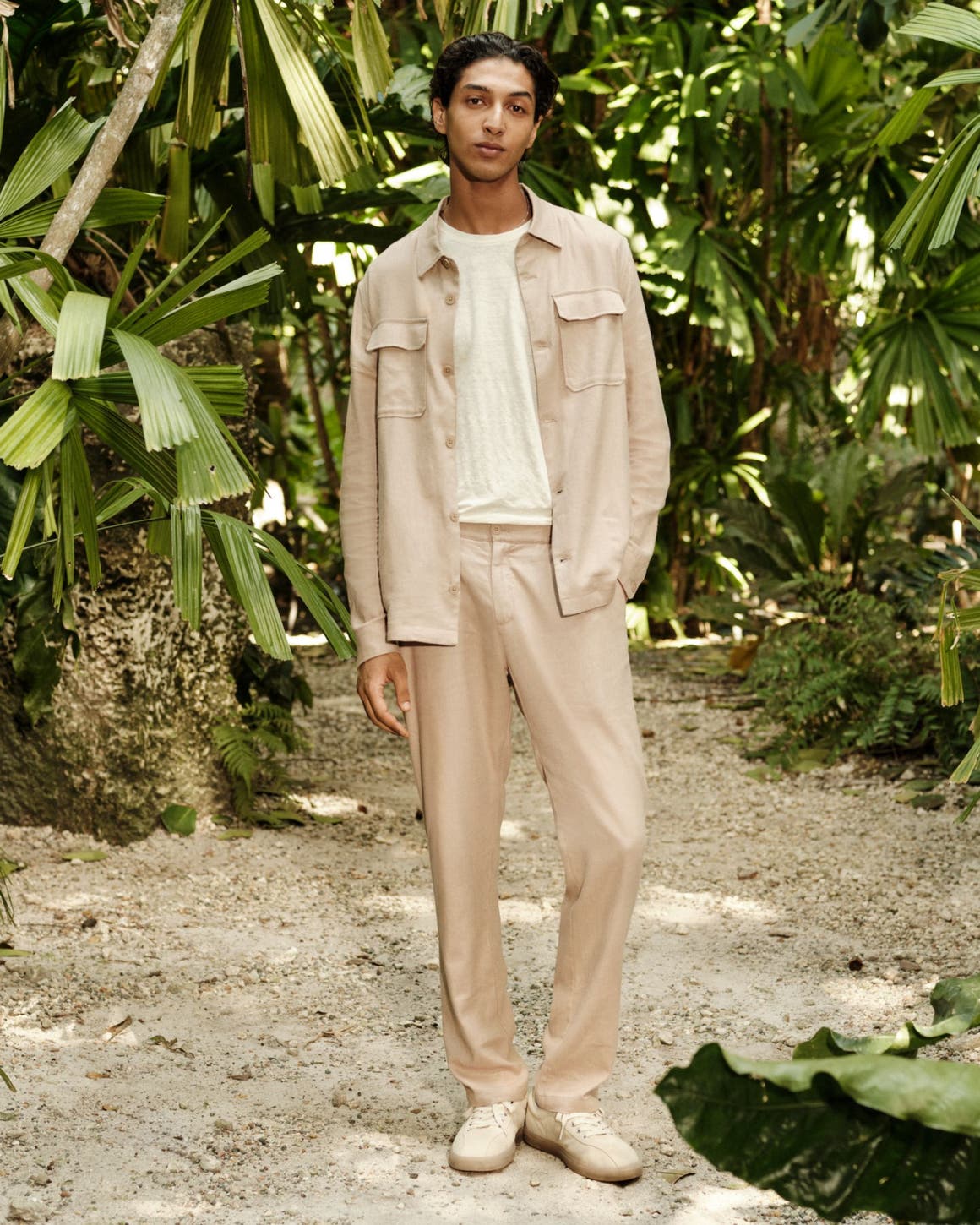 A man wearing a shirt jacket, T-shirt, relaxed trousers and sneakers.