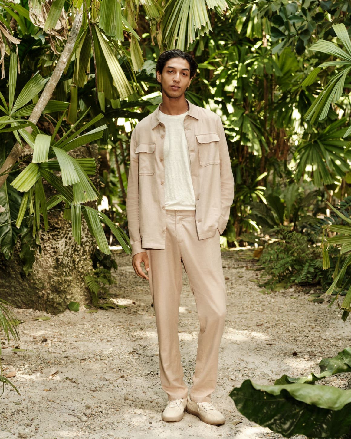 A man wearing a shirt jacket, T-shirt, relaxed trousers and sneakers.