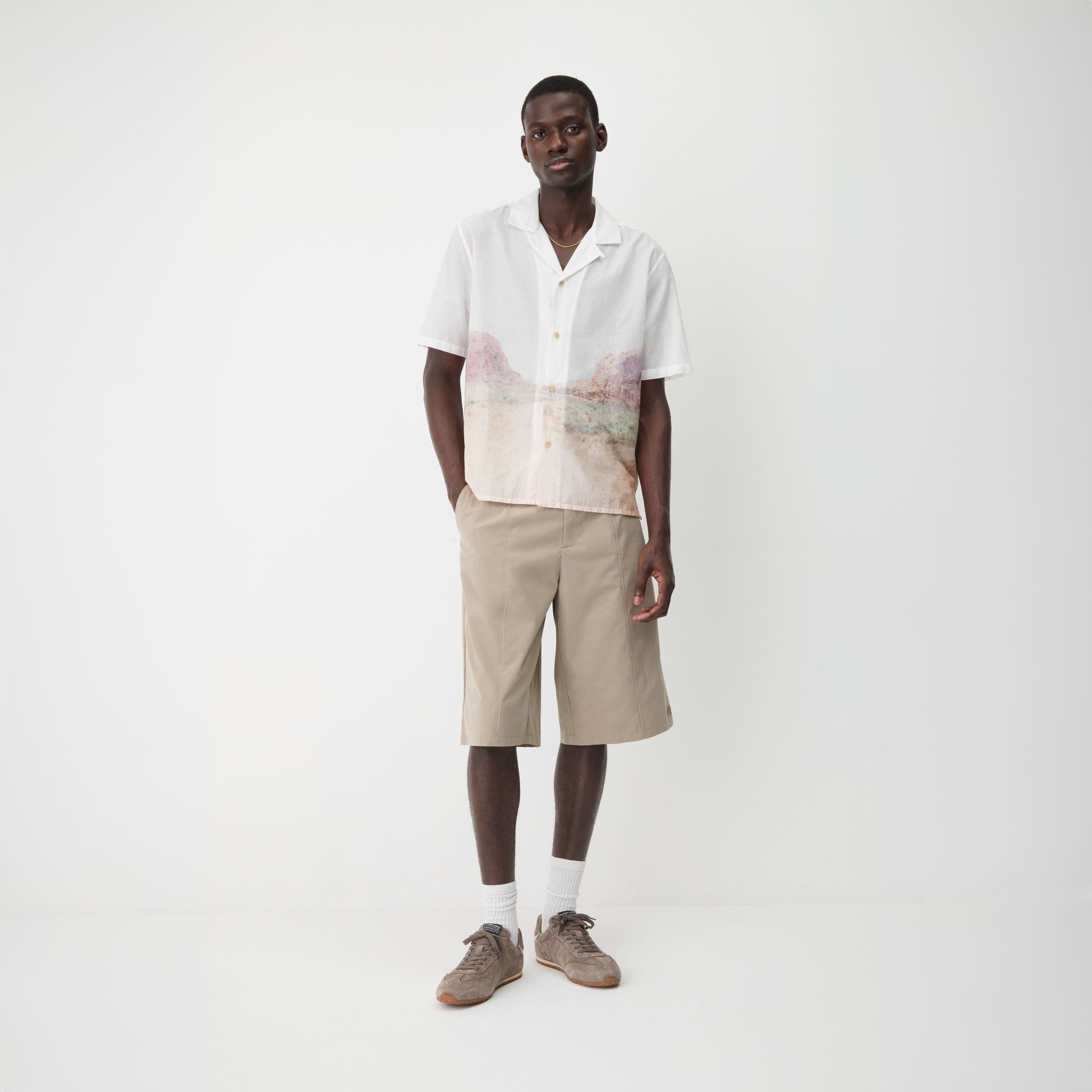 A man wearing beige shorts with a white camp shirt.