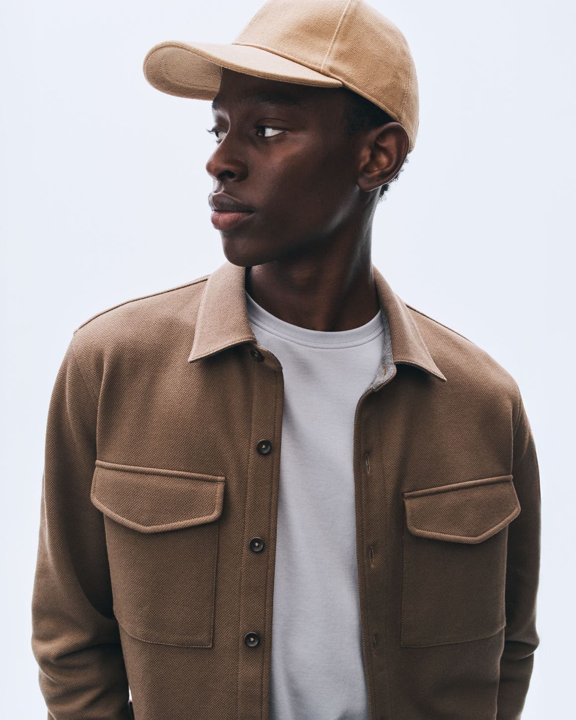 Man in a shirt jacket, T-shirt and baseball cap.