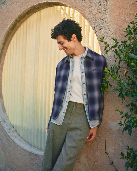 Man wearing a flannel shirt, denim shirt, T-shirt and suit pants.