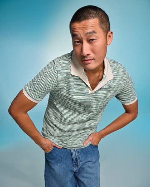 A man wearing a green patterned polo shirt and blue jeans.