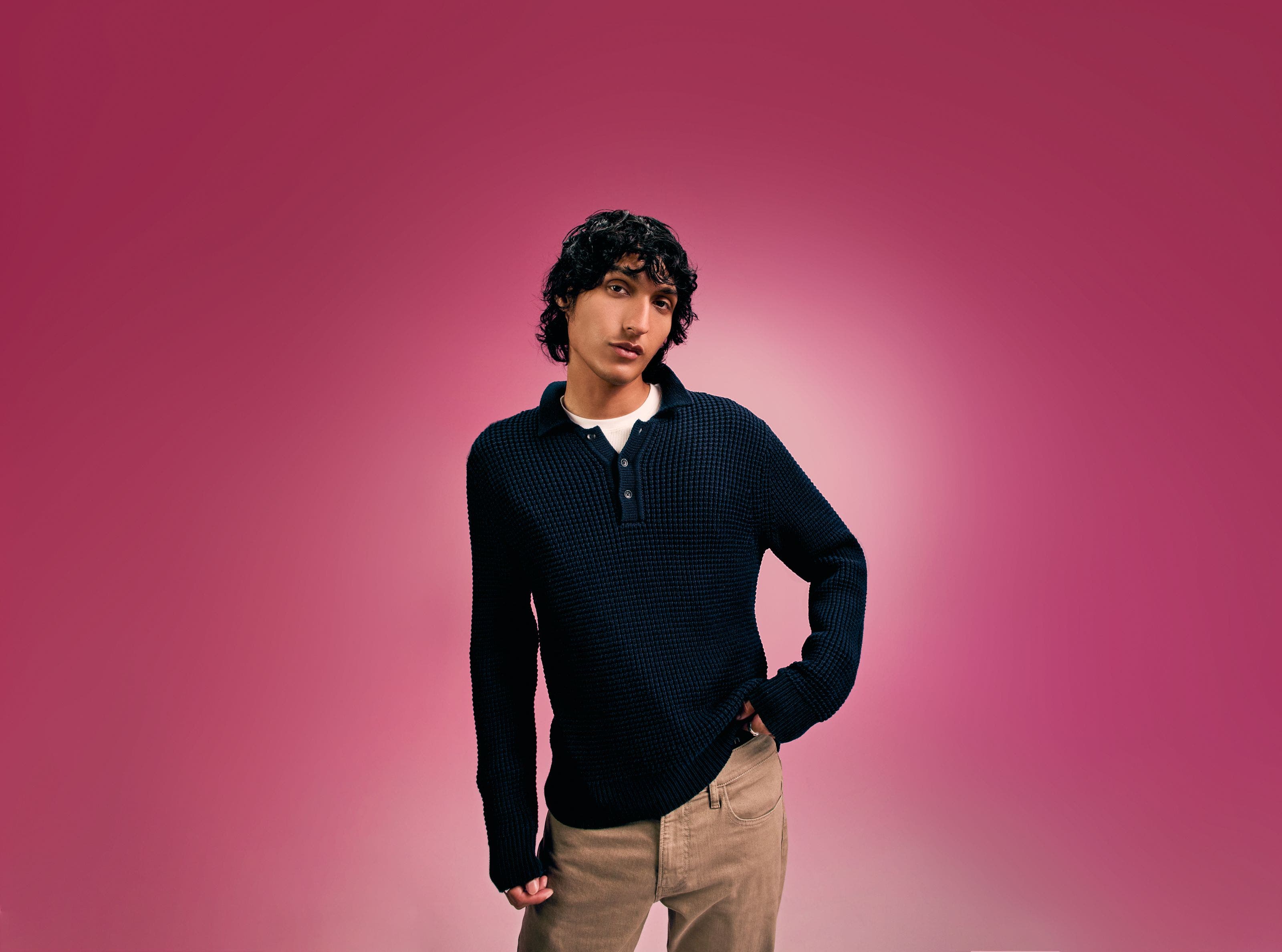 A man wearing a black sweater with tan pants. 