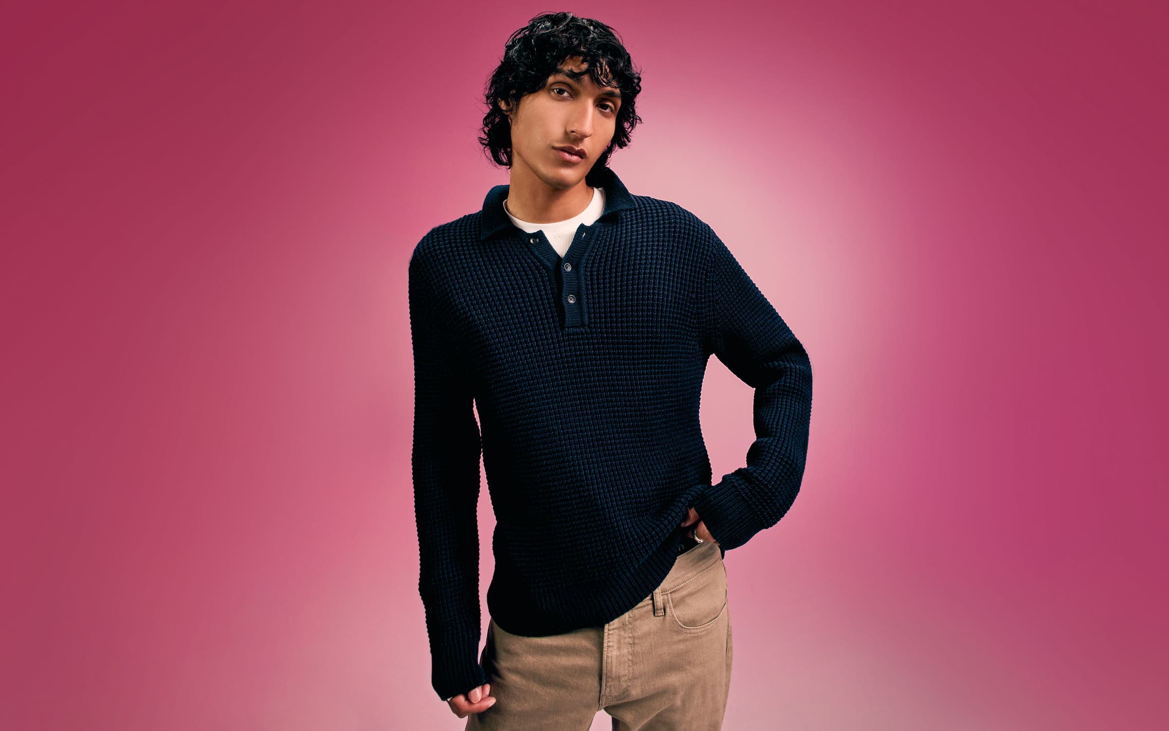 A man wearing a black sweater with tan pants. 