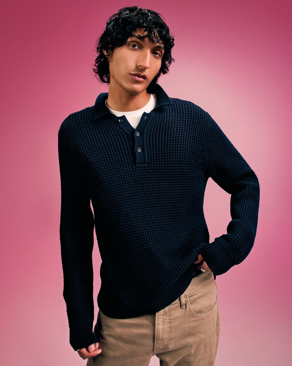 A man wearing a black sweater with tan pants. 