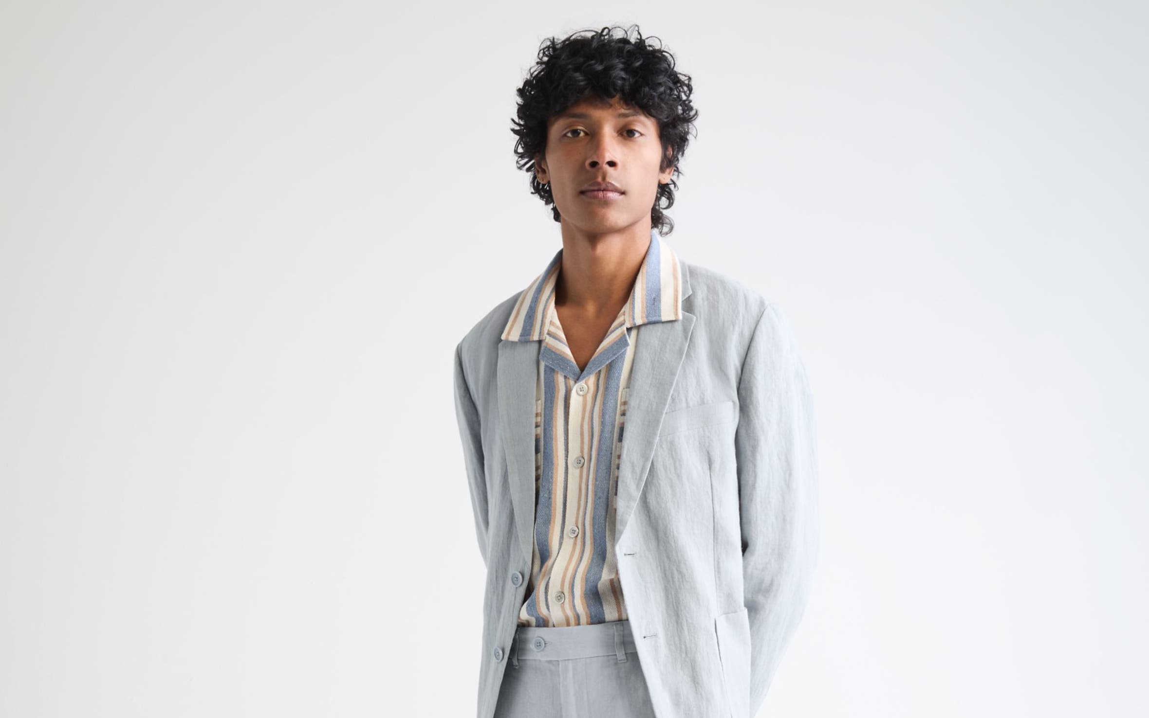 Man wearing a light blue suit with a striped shirt.