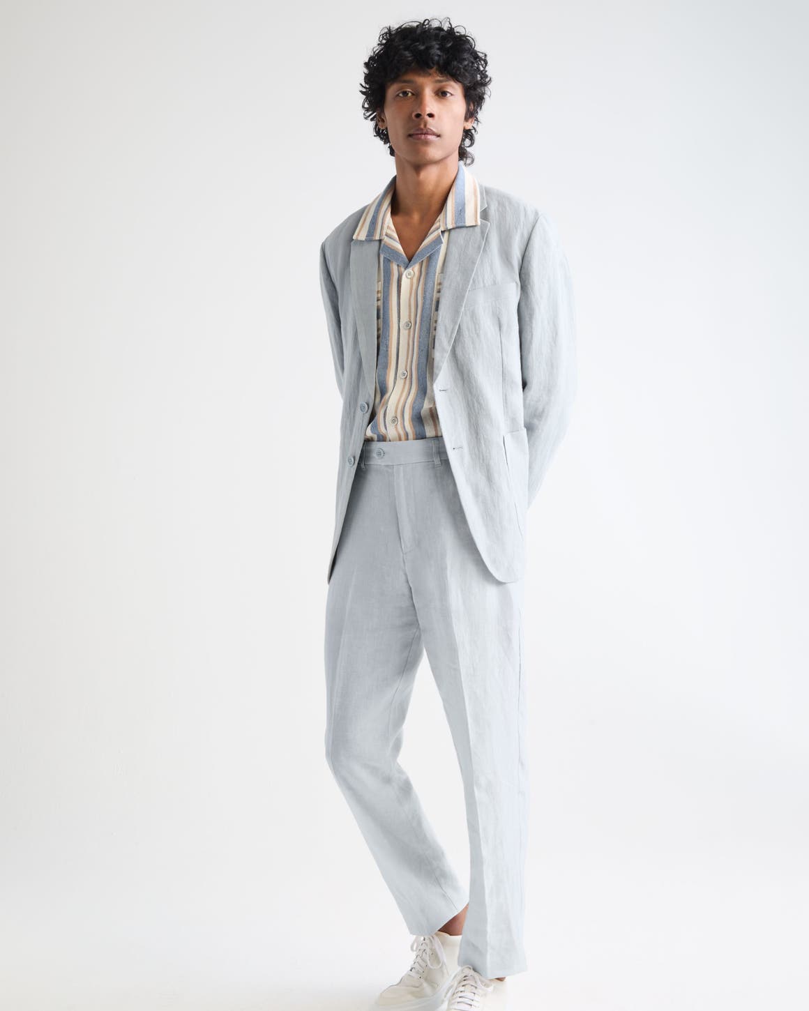 Man wearing a light blue suit with a striped shirt.