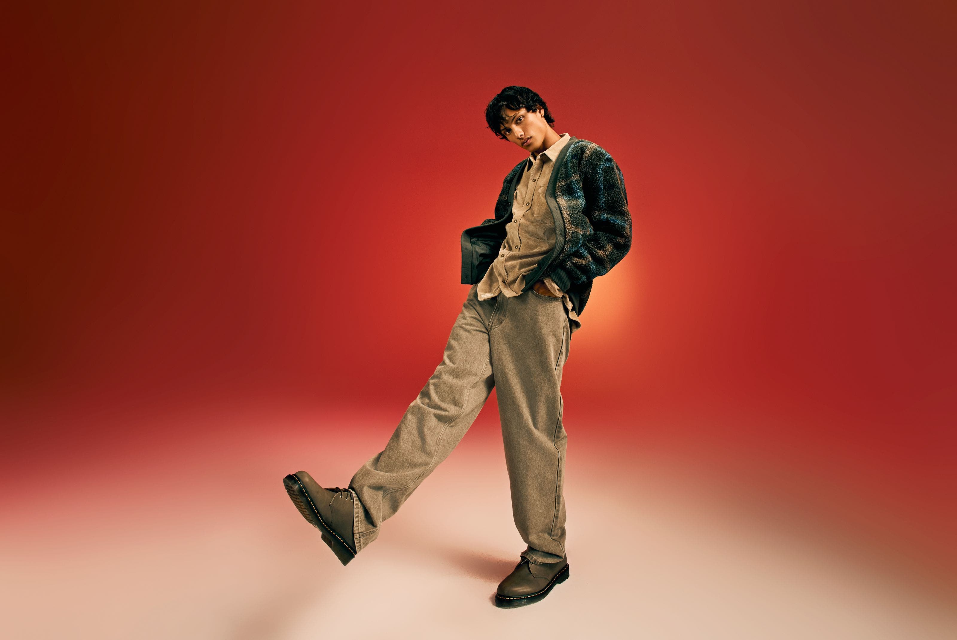 A man wearing a jacket with a button-front shirt and jeans.