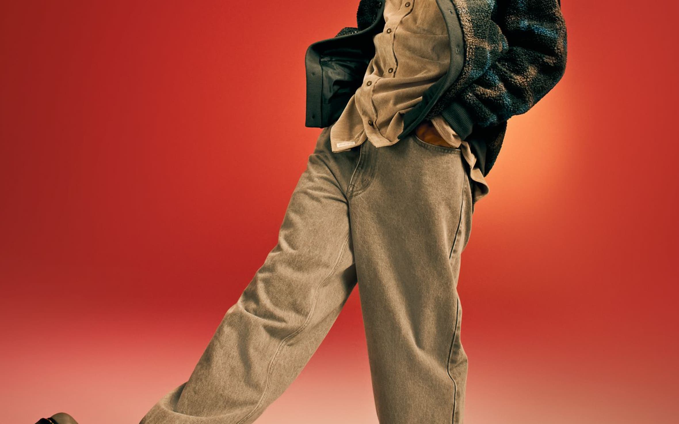 A man wearing a jacket with a button-front shirt and jeans.