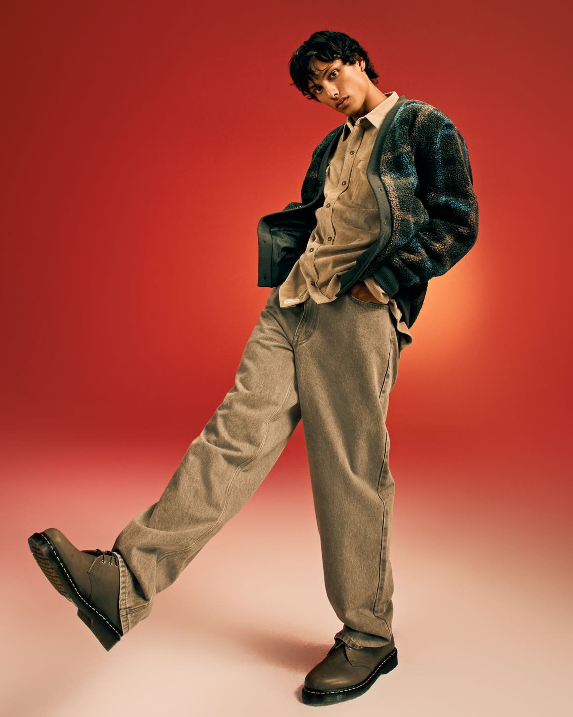 A man wearing a jacket with a button-front shirt and jeans.