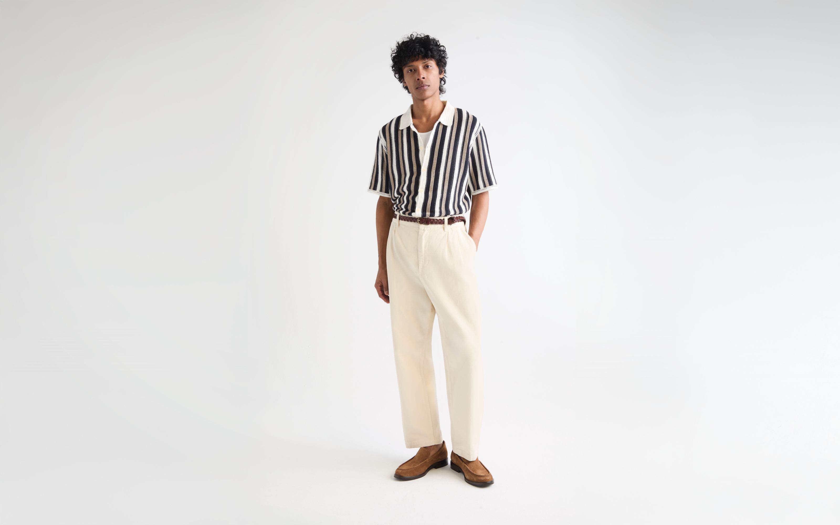 Man wearing a striped polo sweater and cream pants.