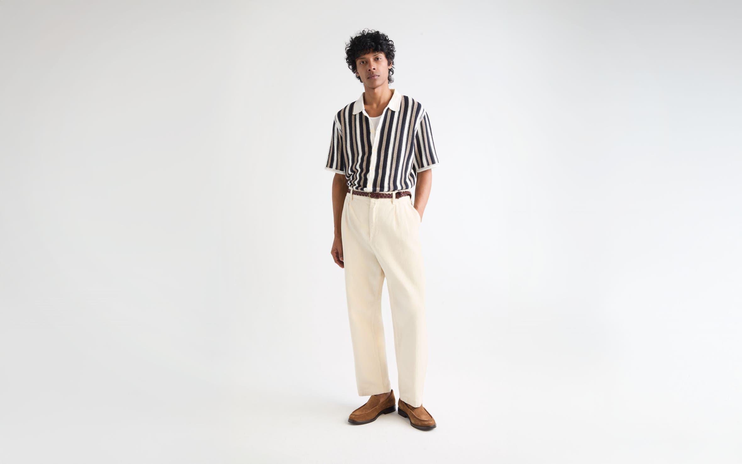 Man wearing a striped polo sweater, cream pants and brown suede loafers.