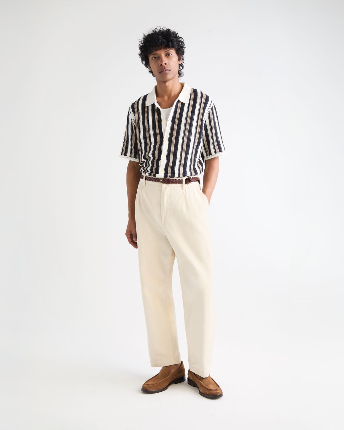 Man wearing a striped polo sweater, cream pants and brown suede loafers.