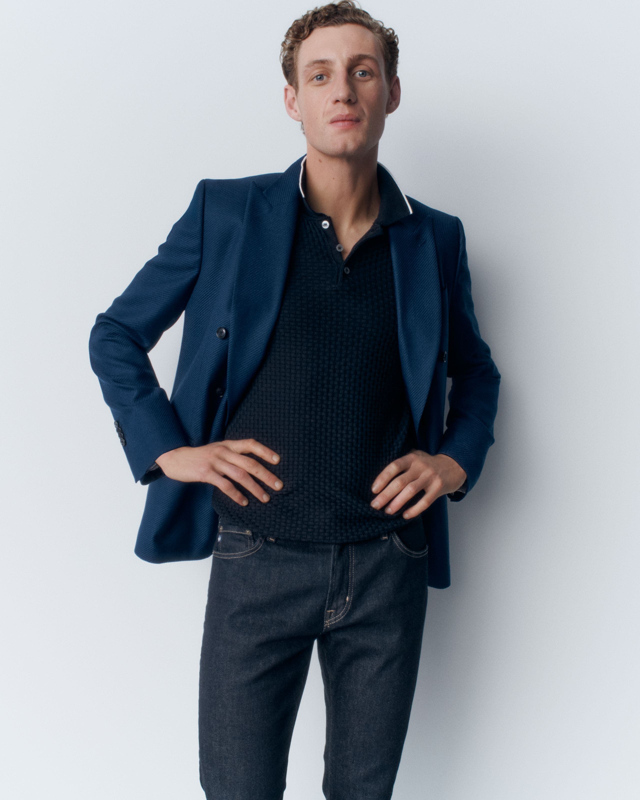 A man in a blue polo, jacket and jeans. 