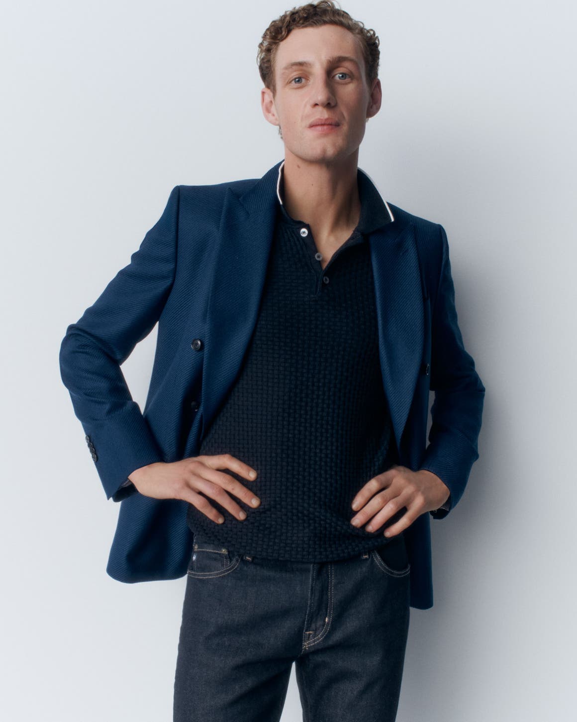 A man in a blue polo, jacket and jeans.