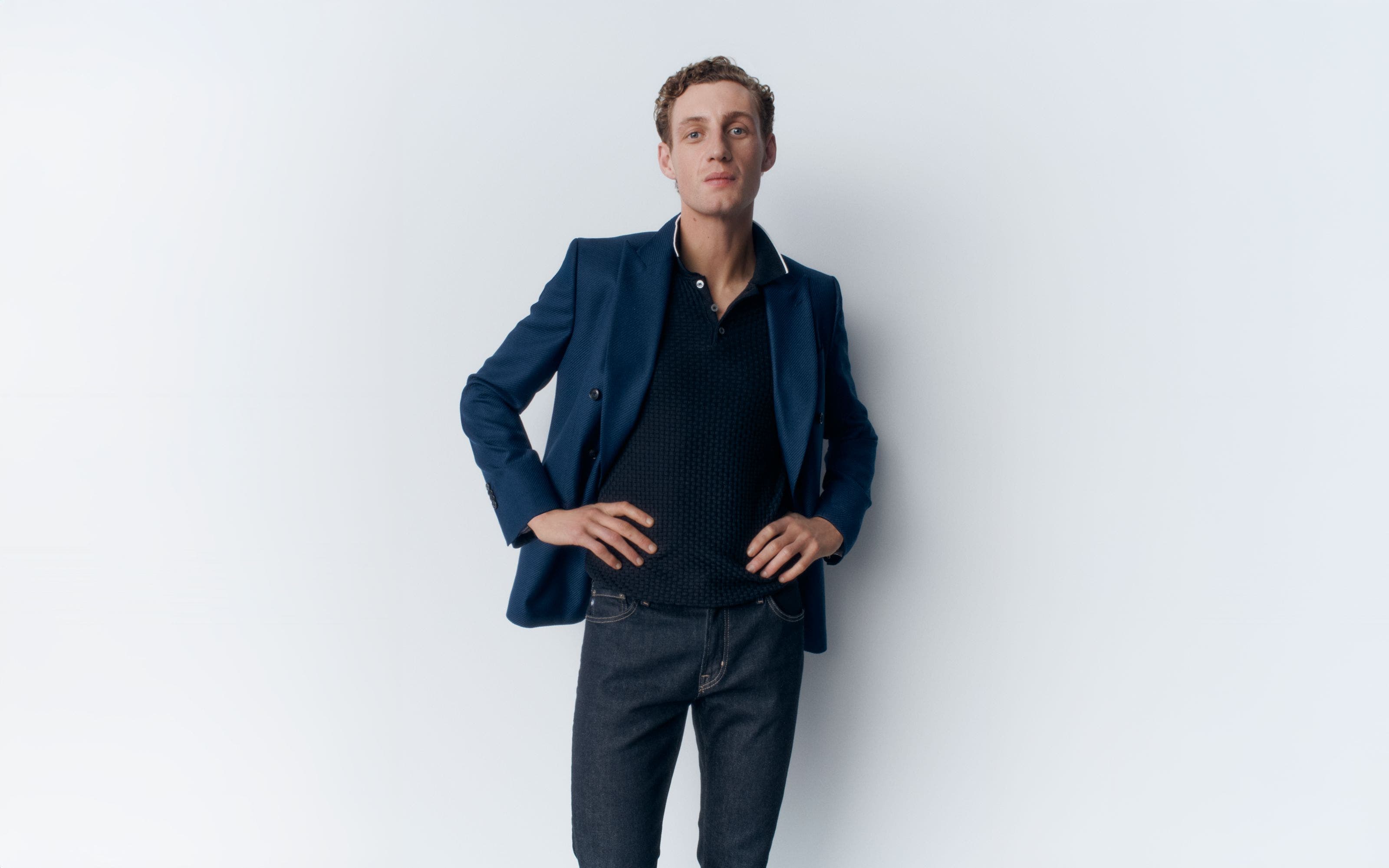 A man wearing a polo, blazer and jeans.