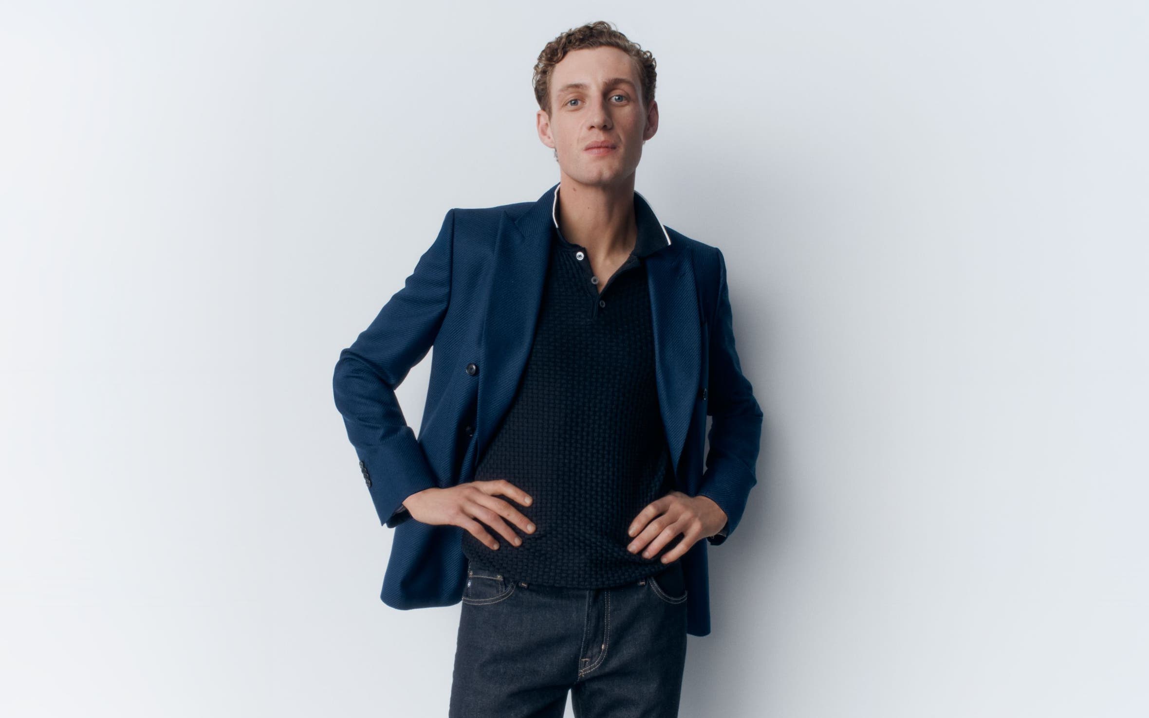 A man wearing a polo, blazer and jeans.