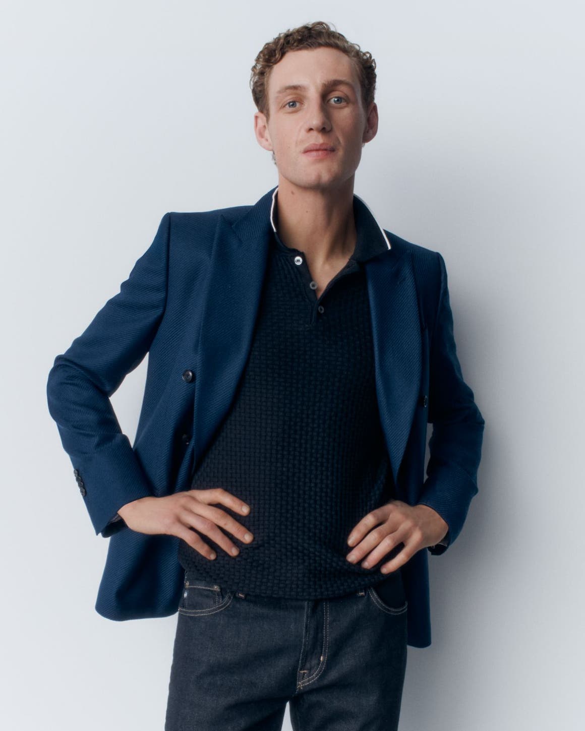 A man wearing a polo, blazer and jeans.